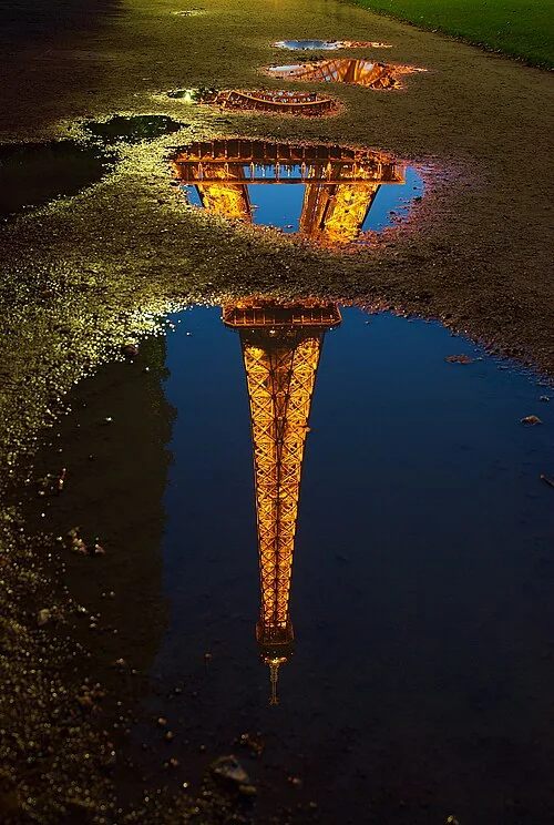 Reflection of the Eiffel tower in a water puddle. Paris, France.