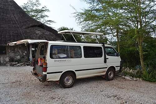 Game viewer vehicle parked at the Lions Bluff Lodge, in LUMO Community Wildlife Sanctuary, Kenya. The sunroof and trunk door is open.
